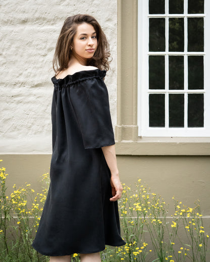 Model draagt multiway zwart / antraciet zijden jurk No.6 van OAXO, off-shoulder gestyled.