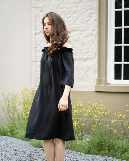 Model draagt multiway zwart / antraciet zijden jurk No.6 van OAXO, off-shoulder gestyled.