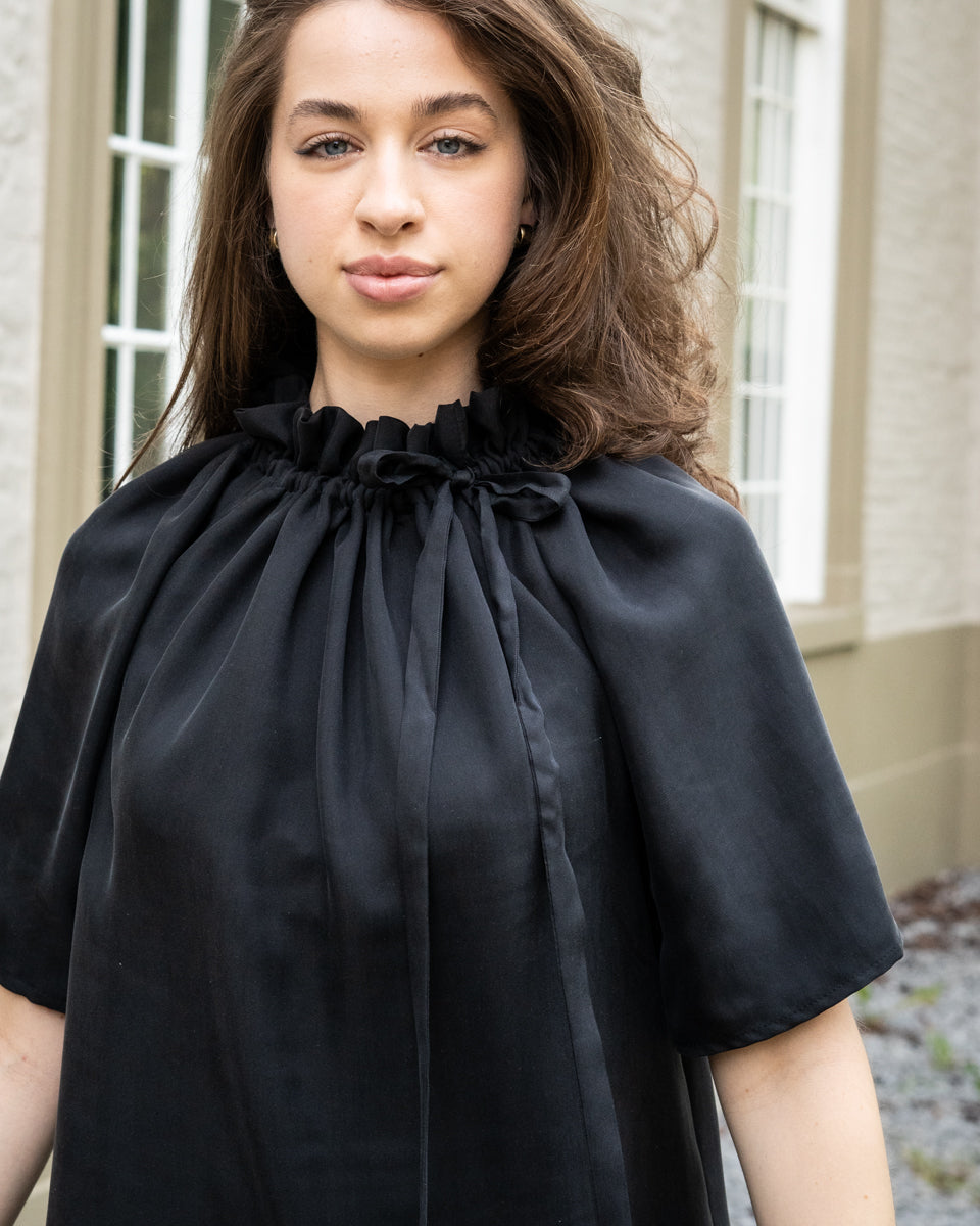 Model draagt zwart / antraciet zijden jurk No.6 van OAXO, elegant gestyled met strik.