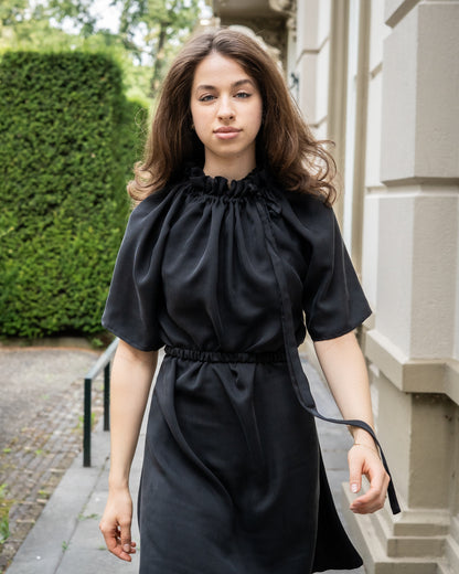 Model draagt multiway zwart / antraciet zijden jurk No.6 van OAXO, met hoge kraag gestyled.