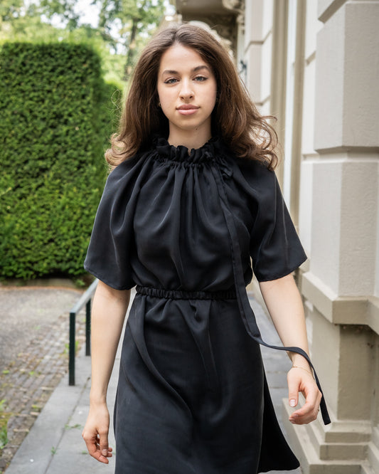 Model draagt multiway zwart / antraciet zijden jurk No.6 van OAXO, met hoge kraag gestyled.