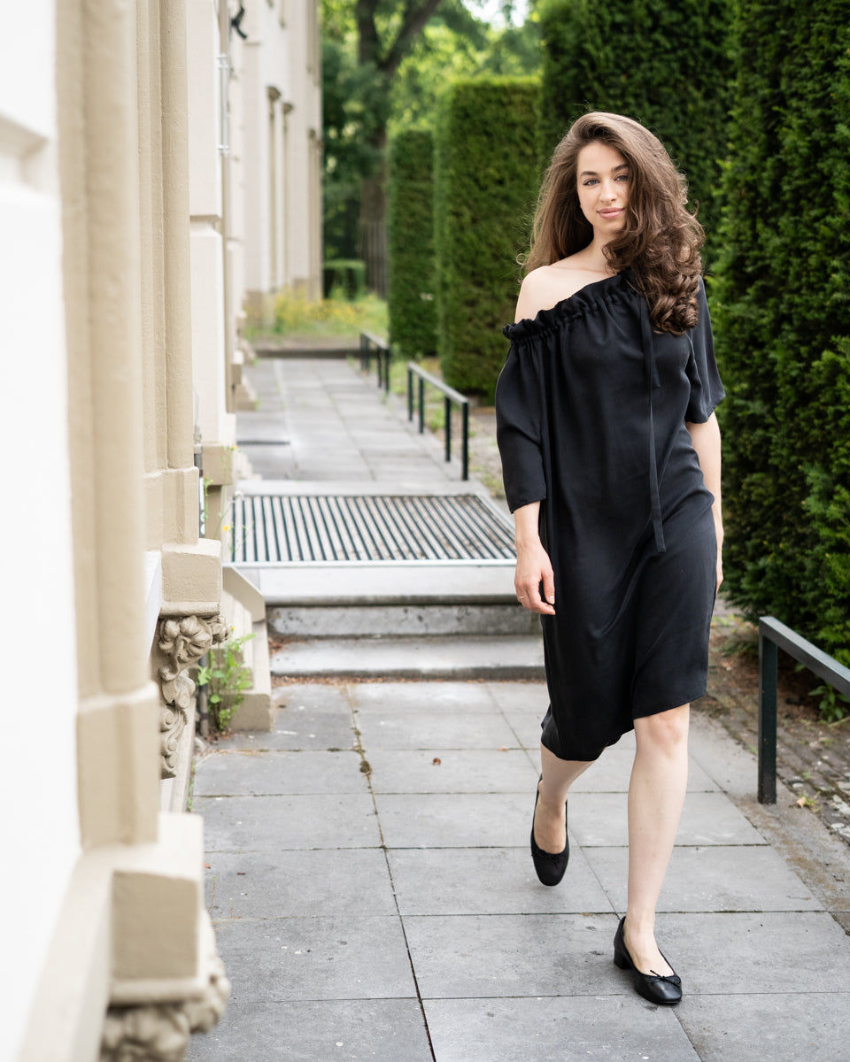Model draagt multiway zwart / antraciet zijden jurk No.6 van OAXO, one-shoulder gestyled.